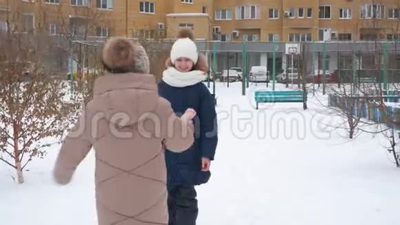 快乐的女朋友在城市的冬天的街道上的雪街见面校园女孩拥抱户外迎接冬天视频的预览图