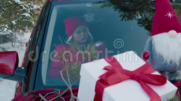 冬天森林里戴着圣诞玩具的可爱少女在红车旁视频的预览图