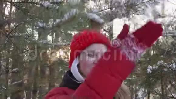 冬林中嬉戏的年轻女子摇着雪白的树枝微笑少女少年玩松树枝视频的预览图