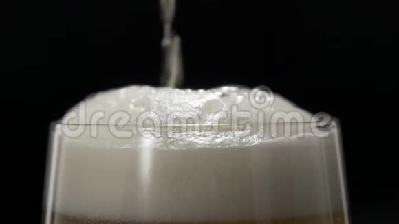 啤酒倒入带有白色泡沫的玻璃杯中啤酒倒在玻璃杯里视频的预览图