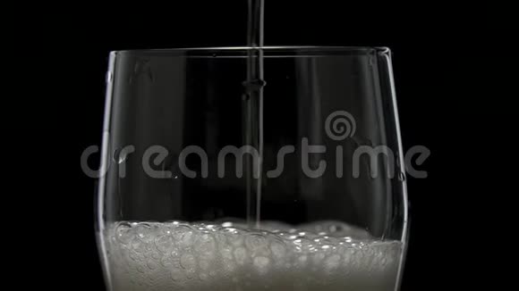 一杯啤酒的特写镜头在缓慢的运动中泡沫啤酒倒入带有白色泡沫的玻璃杯中视频的预览图