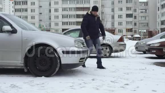 冬天人们在院子里的停车场里试图打开他的车的引擎盖由于天气寒冷船篷冻僵了视频的预览图