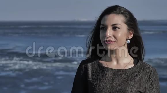 一个穿着黑色衣服的年轻女孩站在岸边在背景海洋里阳光明媚的一天视频的预览图