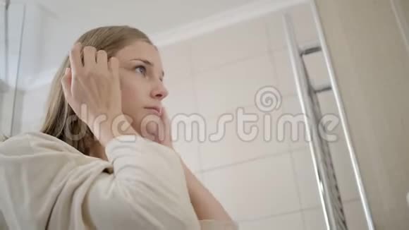 金发女孩把头发留在耳朵后面检查化妆视频的预览图