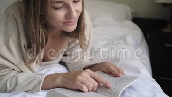 金发女孩看书手指在床单上视频的预览图