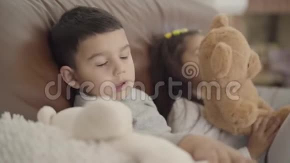 一个可爱的中东男孩和他的妹妹坐在教练和玩玩具的特写脸幼儿开支视频的预览图