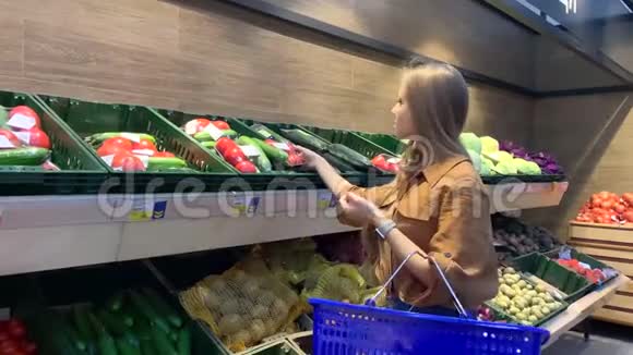 带着购物篮在杂货店挑选新鲜蔬菜的年轻女子视频的预览图