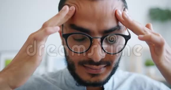 不快乐的阿拉伯人戴眼镜的特写肖像摸着头感到头痛视频的预览图