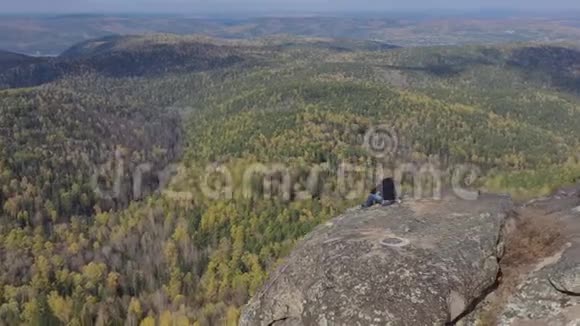 一个孤独的男性登山者坐在山顶上欣赏峡谷的美丽景色视频的预览图