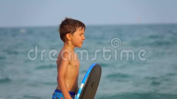 男孩正在用木板躲避海水的飞溅视频的预览图