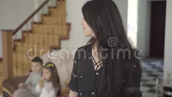 微笑的中东女人淡褐色的眼睛和长长的黑发看着她的孩子坐在背景和视频的预览图
