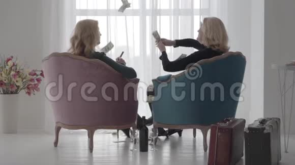 高加索富婆坐在舒适的扶手椅上扔钱的背影幸福富婆消费视频的预览图