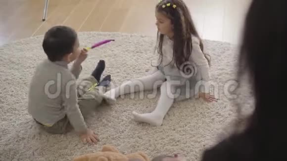 两个可爱的中东孩子在家里的软地毯上玩派对哨子友好的兄弟姐妹免费视频的预览图