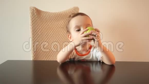 小卷曲可爱的女孩坐在椅子上吃绿色苹果视频的预览图