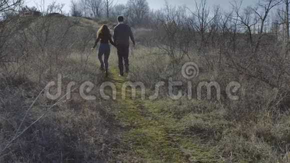 年轻夫妇牵着手爬上一座小山阳光明媚的春天视频的预览图
