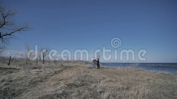 一对年轻夫妇穿着深色的衣服沿着海滨散步阳光明媚的一天视频的预览图