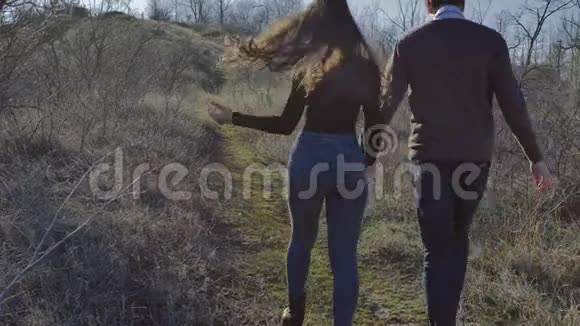 年轻夫妇牵着手爬上一座小山阳光明媚的春天视频的预览图