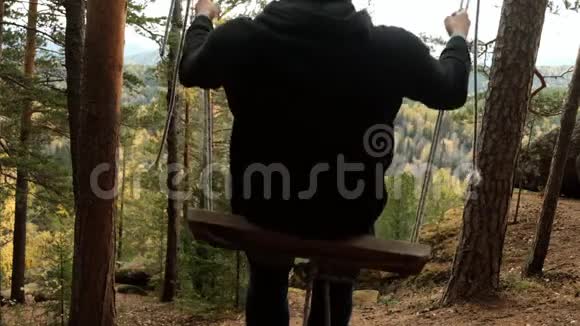 一个年轻的快乐男人在森林里摇摆在一个山峡里欣赏着秋天的风景视频的预览图