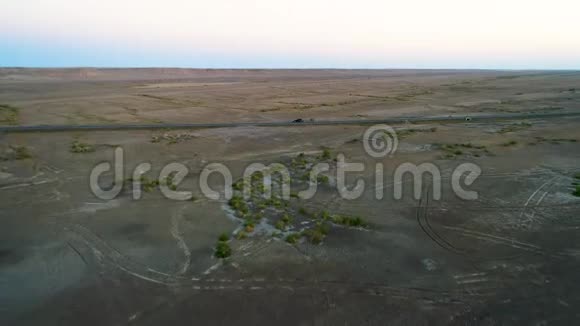 在干旱的沙漠中间的一条空路上驾驶汽车的鸟瞰图视频的预览图