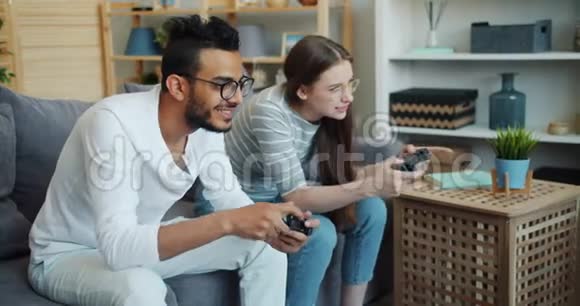 阿拉伯男孩和可爱的女朋友在家玩电子游戏视频的预览图