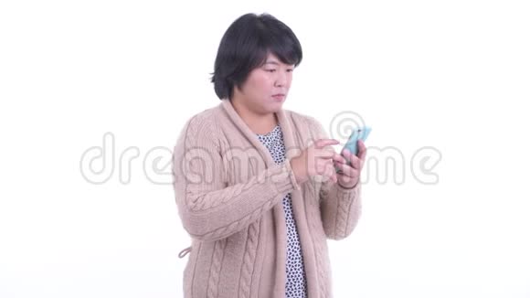 穿着超重的亚洲女人在冬天用电话接坏消息视频的预览图