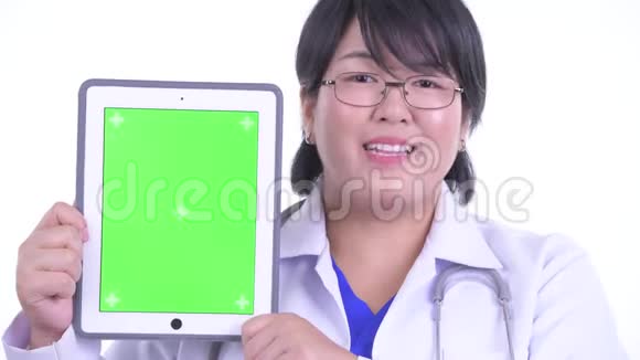 一位快乐超重的亚洲女医生一边讲着数字平板电脑视频的预览图