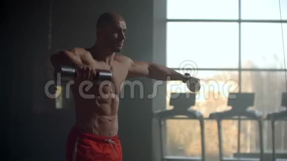 强壮有目标的男性健美运动员举起哑铃手握双手训练肩膀和背部视频的预览图