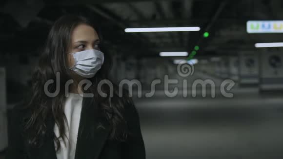 冠状病毒流行期间在地下空停车场戴面罩的妇女视频的预览图