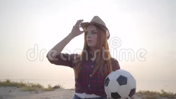 夏天晚上年轻美丽的女孩带着足球来到海滩上放松和享受乐趣的肖像视频的预览图