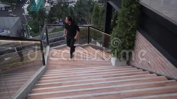 一位留着黑色长发的亚洲男性正从曼谷天景餐厅的屋顶楼梯上走过来视频的预览图