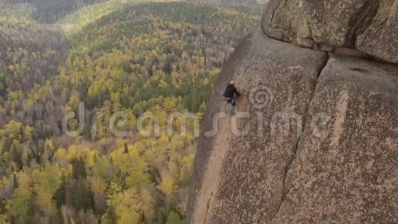一个人爬上一块岩石俯瞰秋天的森林视频的预览图