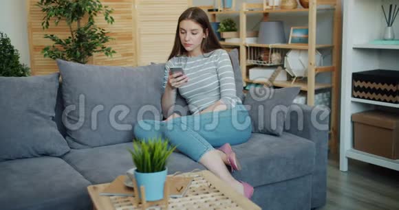 年轻女士在家沙发上用智能手机表情严肃视频的预览图