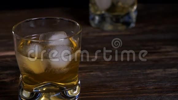 冰块和金色麦芽威士忌一起倒入玻璃杯中视频的预览图