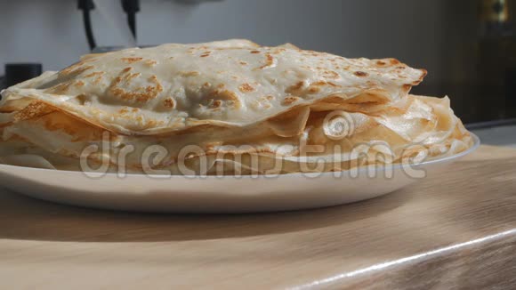 白色盘子上的一堆煎饼上面有一个新煎饼和一块奶油黄油传统俄语视频的预览图