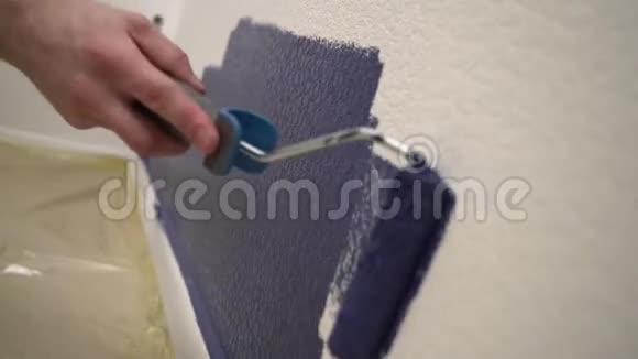 人用蓝色油漆把白色的墙漆成蓝色视频的预览图