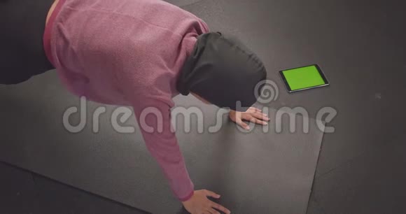 年轻坚定的穆斯林女性戴着头巾做木板运动的特写照片用手机追踪应用程序视频的预览图