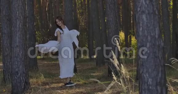 快乐微笑的白种人女孩在夏天的森林里的树木之间旋转微笑着神秘的独立视频的预览图