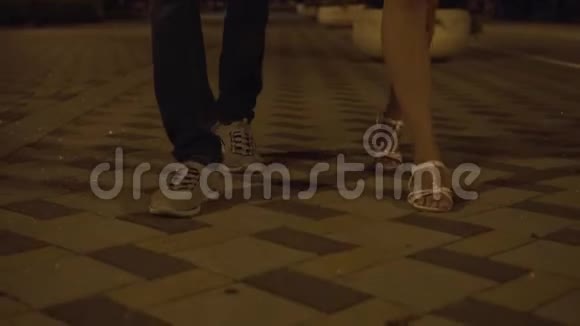 一个男人和一个女孩的腿晚上在铺路石上行走视频的预览图