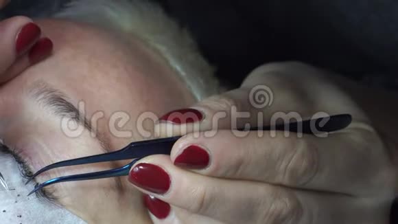 用镊子粘合人造睫毛化妆程序睫毛延伸长睫毛的女人眼视频的预览图