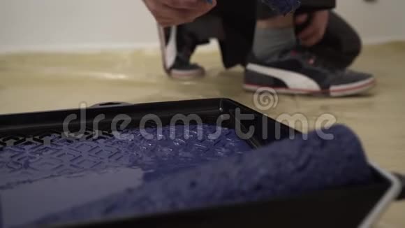 人用小油漆滚筒从油漆桶或托盘中取出蓝色油漆视频的预览图