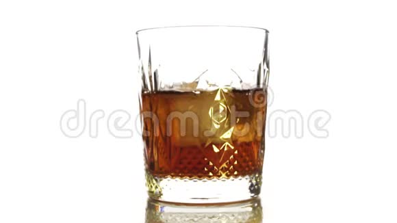 特写镜头冰块在一杯威士忌中旋转融化孤立于白色背景1视频的预览图
