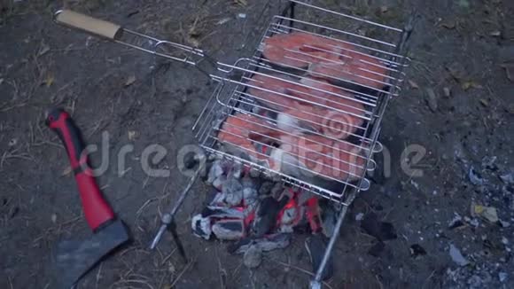 令人兴奋的红鱼是在木桩上煮熟的在烧烤架上烤三文鱼视频的预览图