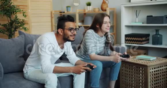 女孩和男孩混合种族的夫妇在家玩游戏使用操纵杆视频的预览图