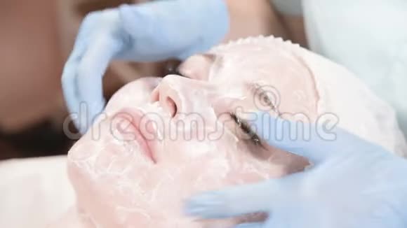 这位美容师的女孩负责清洁和滋润皮肤敷一个带特殊面膜视频的预览图