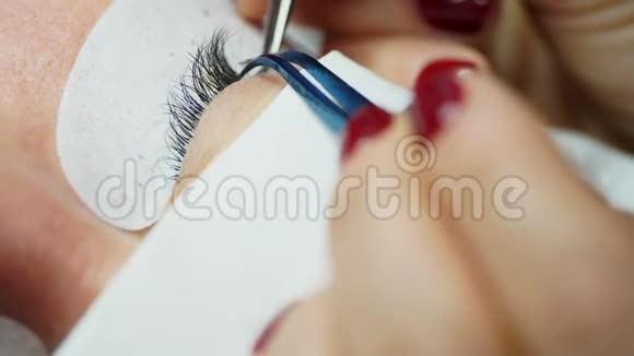 用镊子粘合人造睫毛化妆程序睫毛延伸女人的眼睛长着睫毛视频的预览图