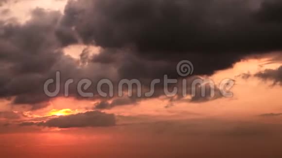 橙色的大太阳随着灰色的乌云落在红色天空的地平线上4K录像视频的预览图