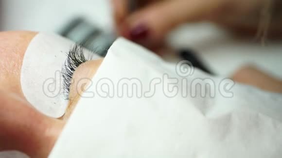 用镊子粘合人造睫毛化妆程序睫毛延伸女人的眼睛长着睫毛视频的预览图