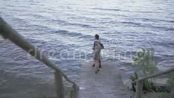 年轻夫妇走在小码头上聊天情侣们一起在海滨度过时光视频的预览图