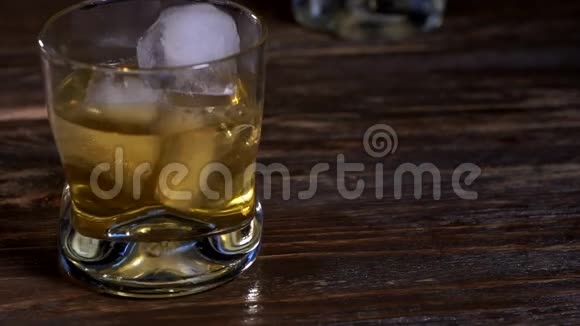 冰块和金色麦芽威士忌一起倒入玻璃杯中视频的预览图