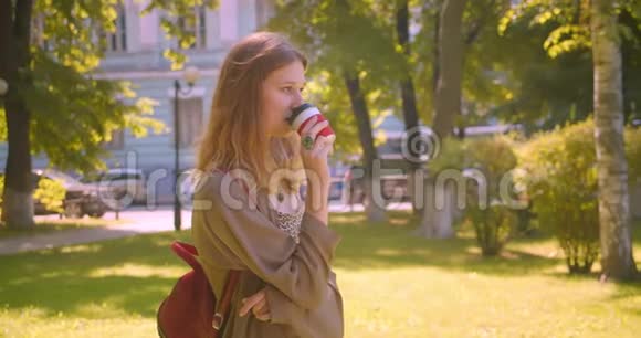 特写侧景照片年轻可爱的白种人女性看着镜头喝着咖啡幸福地站在里面视频的预览图